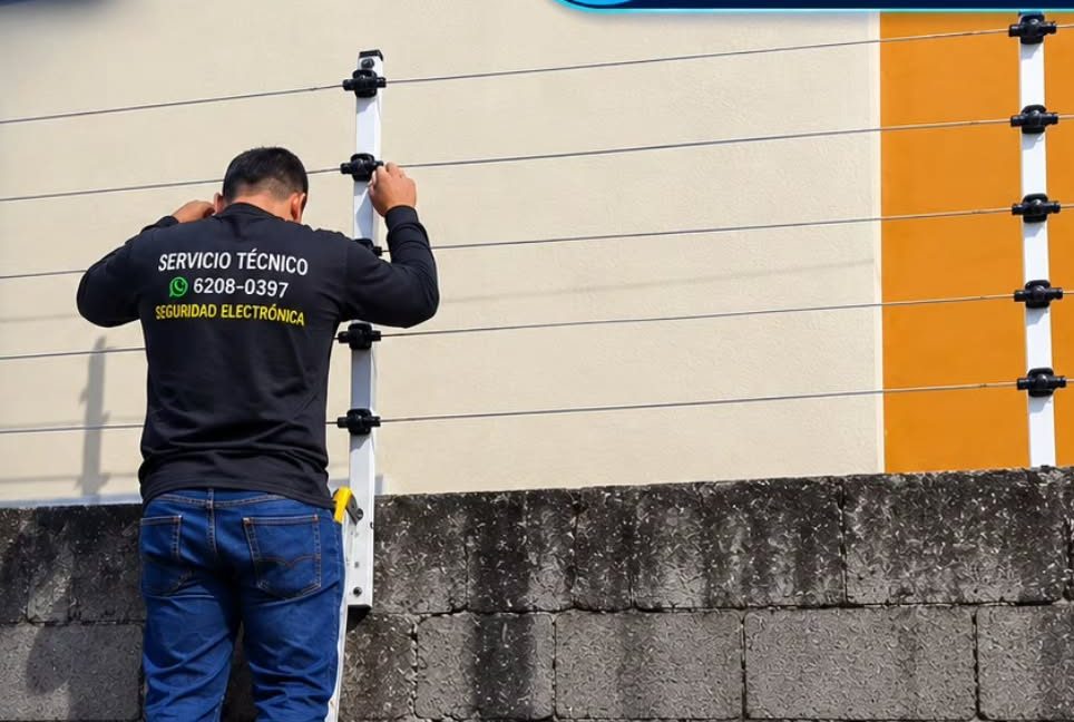 Técnico instalando un cerco eléctrico sobre un muro